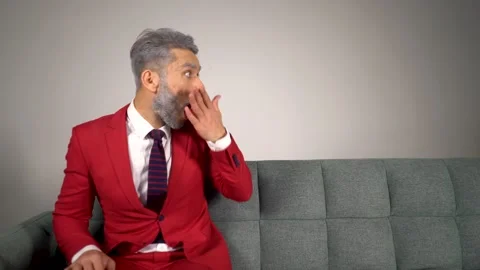 Handsome blond bearded man in red suit on sofa looking to the side in copy space Stock Footage 167651840