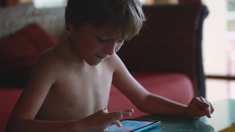 Handsome blond boy looking at screen of modern tablet pc. Plays in some game Stock Footage 78508674