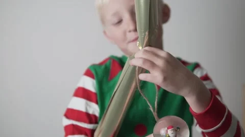 Handsome blond boy opens his Christmas gift wrapped in wrapping paper Stock Footage 143699462