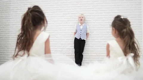A handsome blond boy is standing by a white brick wall and telling something Stock Footage 100335876
