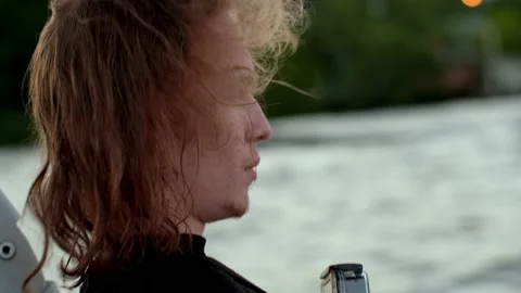A handsome blond curly guy rolls on a boat and looks at the waves. Stock Footage 205611048