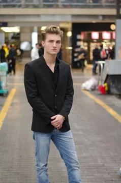 Handsome blond young man standing in station or shopping center Stock Photos