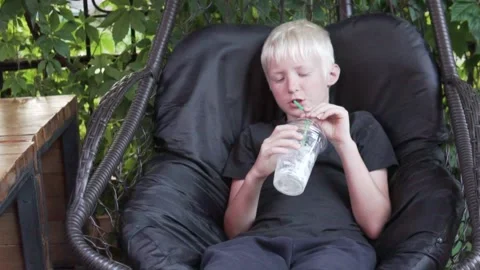 A handsome blonde boy drinks a milk cocktail in a cafe Stock Footage 160625957