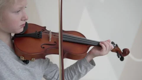 Handsome blonde boy learns to play the violin in the new house Stock Footage 145385975