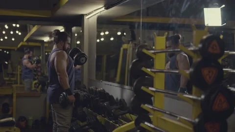 Handsome bodybuilder with beard and man-bun doing biceps exercise using dumbb Stock Footage 161317076