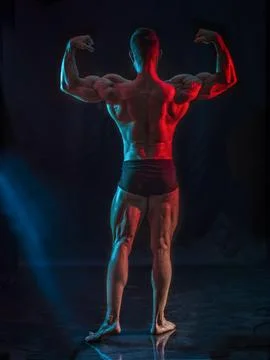 Handsome bodybuilder doing classic back double biceps pose, looking away, on Stock Photos