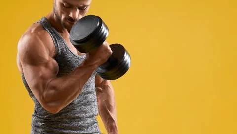 Handsome bodybuilder doing exercise with dumbbell Stock Photos