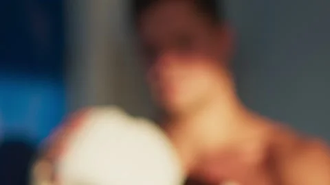 Handsome boxer man puts on white gloves to punching bag outdoor in industrial Video stock 196840285