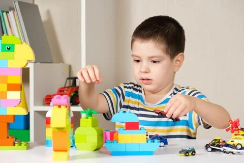 A handsome boy of 4 years old plays with cars and a construction set, games of 库存照片