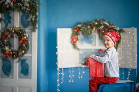 Handsome boy 7 years old in red pants in winter scenery holding a red box in his Foto stock