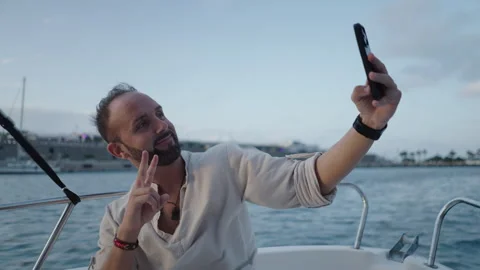 Handsome boy with beard takes a selfie on the boat Video stock 265907273
