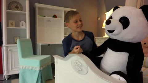 Handsome boy on the bed. A blond boy talking to a toy bear. Stock Footage 79617497