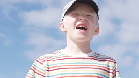 Handsome boy blond in a cap on his head against the sky Stock Footage 106770784