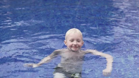 Handsome boy blond swims in the outdoor pool. Stock Footage 106981509