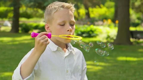 Handsome boy blowing soap bubbles having fun. Child having fun outdoors Video stock 252089787