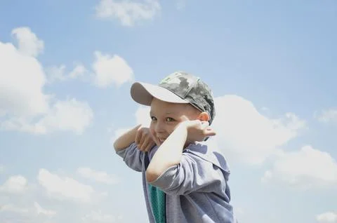 Handsome boy in a cap against a background of blue sky with white clouds Stock Photos
