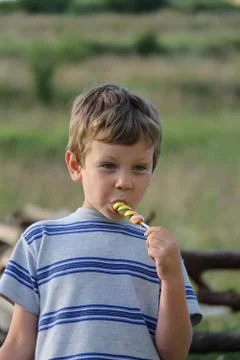 Handsome boy eats colorful candy Stock Photos