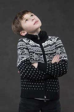 Handsome boy in a knitted jacket on a gray background. Pensive child. School- Stock Photos