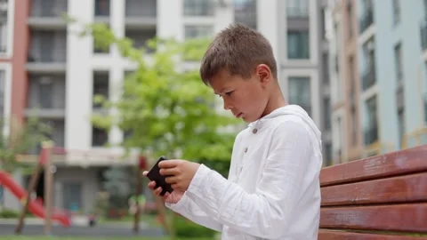 Handsome Boy Playing Mobile Game on Smartphone while Sitting at Bench. Stock Footage 249211328