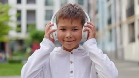 Handsome Boy Putting On the Big White Headphones while Standing Outside. Stock Footage 249353693