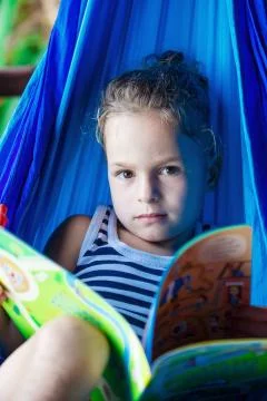 Handsome boy reading a book in a hammock Stock Photos