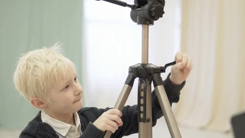 Handsome boy sets up a tripod for the photographer Stock Footage 101046084