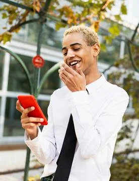 Handsome boy smiling while answering a mobile phone message Stock Photos
