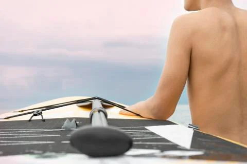 Handsome boy surfer looking for the waves on the sunset Stock Photos