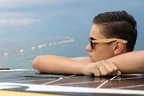 Handsome boy surfer looking for the waves on the sunset Stock Photos