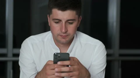 Handsome brunette lingered until night at work in the office holding a phone and Stock Footage 136822053