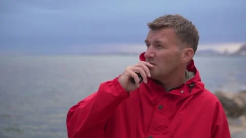 Handsome brunette man in bright red jacket smoking Electronic cigarette against Stock Footage 274055319