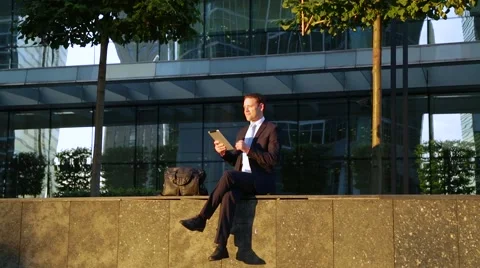 Handsome business man using tablet computer on the street, smiling, laughing 動画素材 68385988