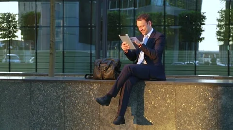 Handsome business man using tablet computer on the street, smiling, laughing Vidéo 68386044