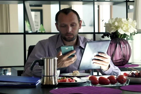 Handsome businessman comparing data on tablet and laptop at home NTSC Stock Footage 44737776