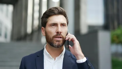 Handsome businessman in formal suit talking on mobile phone standing on city  Stock Footage 314798341