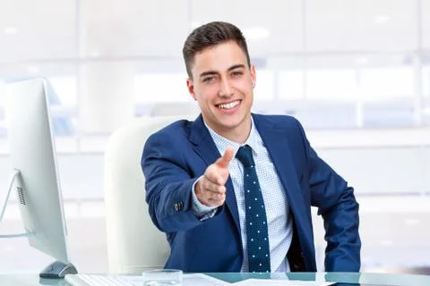Handsome businessman reaching out hand at desk. Stock Photos