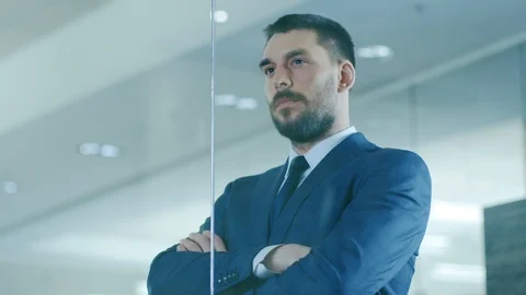 Handsome Businessman in the Suit Looks out of the Office Window. Successful Man Stock Footage