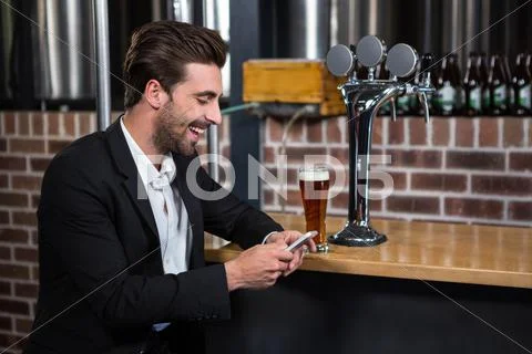 Handsome Businessman Texting On His Phone In A Pub