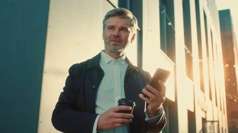 Handsome businessman using smartphone drinking coffee on office break. Corporate Video stock 166523460