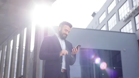 Handsome businessman using smartphone standing near business center. Happy Stock Footage 158236752