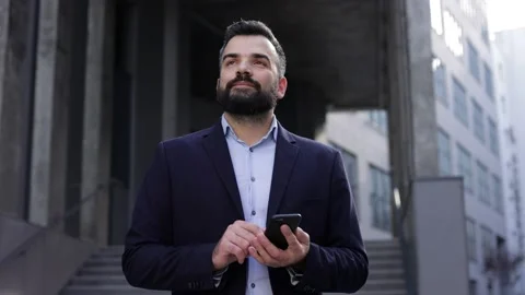 Handsome businessman using smartphone standing near business center. Happy Stock Footage 162467608