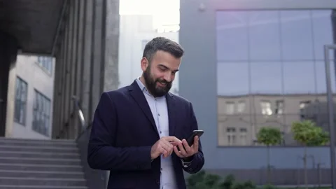 Handsome businessman using smartphone standing near business center. Happy Stock Footage 162467686