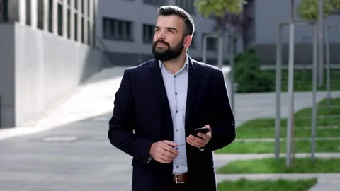 Handsome businessman using smartphone standing near business center. Happy Stock Footage 166097784
