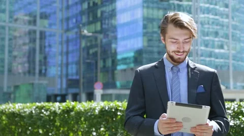 Handsome businessman is using tablet computer near the modern business center Stock-Footage 67583072
