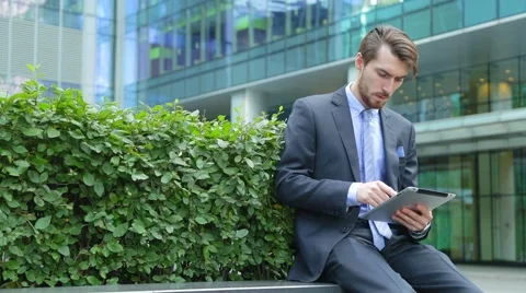 Handsome businessman is using tablet computer near the modern business center Stock Footage 67583154