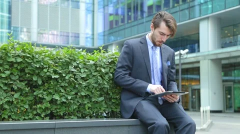 Handsome businessman is using tablet computer near the modern business center Stock Footage 67583160