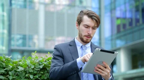 Handsome businessman is using tablet computer near the modern business center Stock Footage 67583219
