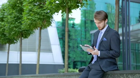 Handsome businessman is using tablet computer near the modern business center Stock-Footage 67583259