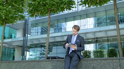 Handsome businessman is using tablet computer near the modern business center Stock-Footage 67583270