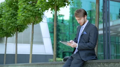Handsome businessman is using tablet computer near the modern business center Stock-Footage 67583280
